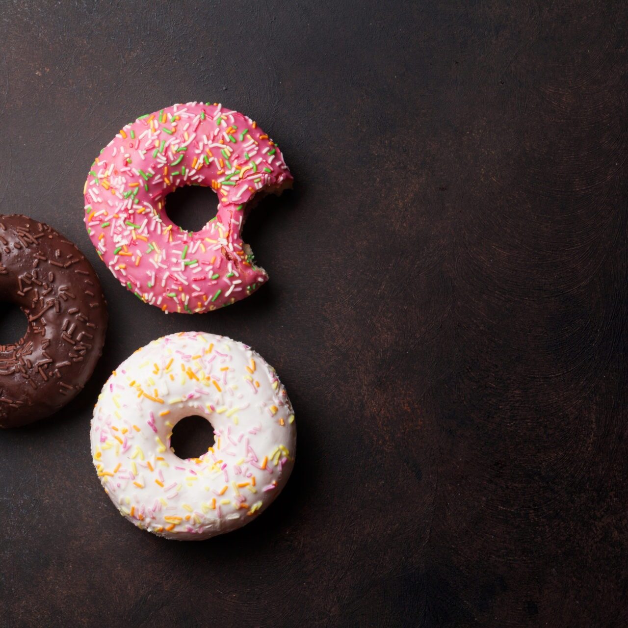 Colorful Donuts Colorful donuts on stone table. Top view with copy space