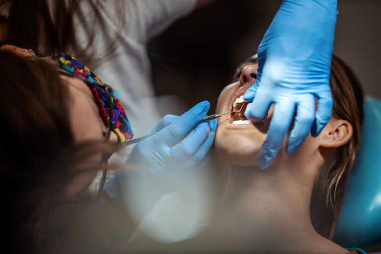 For Healthy Teeth! The beautiful young woman is at the dentist. She sits in the dentist's chair and the dentist sets braces on her teeth putting aesthetic self-aligning lingual locks.